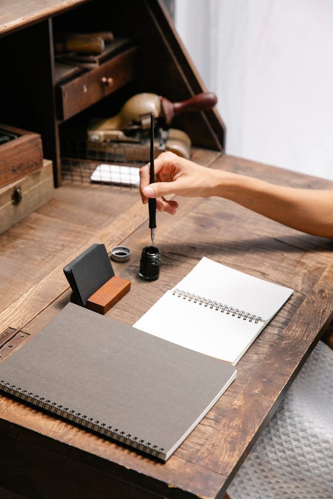 Crop faceless woman dipping pen in inkwell